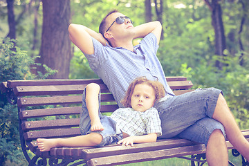 Image showing Father and son playing at the park on bench at the day time.