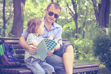 Image showing Father and son playing at the park on bench at the day time.