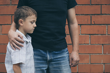 Image showing Portrait of young sad little boy and father sitting outdoors at 