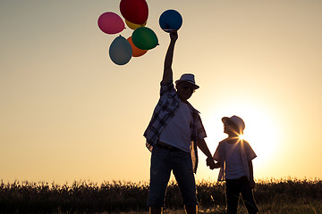 Image showing Father and son standing on the road at the sunset time.