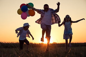 Image showing Father and children running on the road at the sunset time.