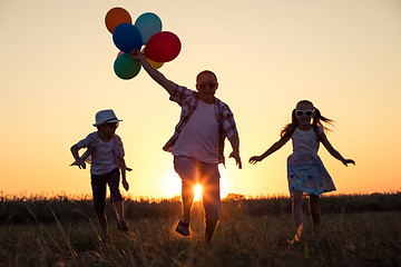 Image showing Father and children running on the road at the sunset time.