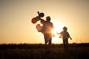 Image showing Father and son running on the road at the sunset time.