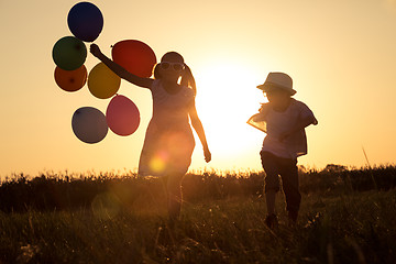 Image showing Silhouette of two happy children which playing on the field at t