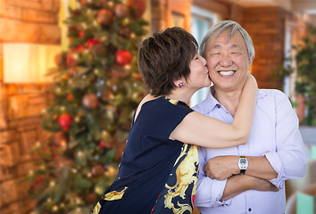 Image showing Happy Senior Chinese Couple Kissing In Front of Decorated Christ