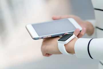 Image showing Woman connecting smart watch and cellphone