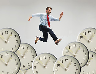 Image showing Businessman running over alarm clock.