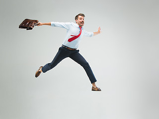 Image showing Businessman running with a briefcase, isolated on gray background