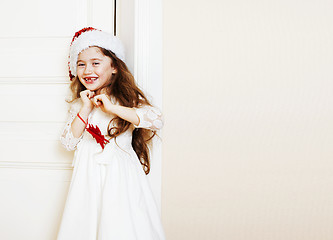 Image showing little cute girl in santas red hat waiting for Christmas gifts. 