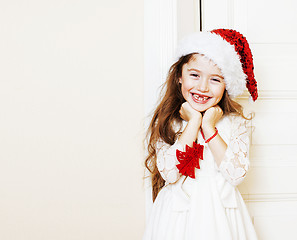 Image showing little cute girl in santas red hat waiting for Christmas gifts. 