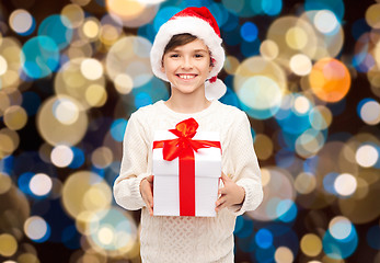 Image showing smiling happy boy in santa hat with christmas gift