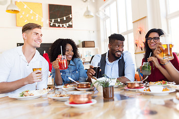 Image showing happy friends eating and drinking at restaurant