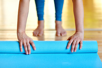 Image showing woman hands rolling yoga mat at gym or studio