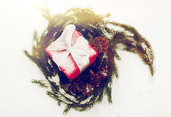 Image showing christmas gift and fir wreath with cones on snow