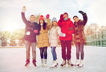 Image showing happy friends ice skating on rink outdoors