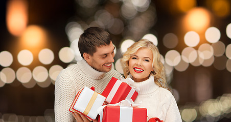 Image showing happy couple in sweaters holding christmas gifts