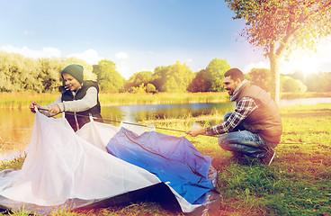 Image showing happy father and son setting up tent outdoors