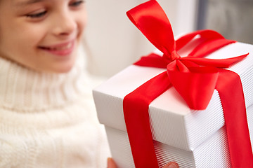 Image showing girl with christmas gift sitting on sill at home