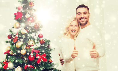 Image showing happy couple showing thumbs up with christmas tree