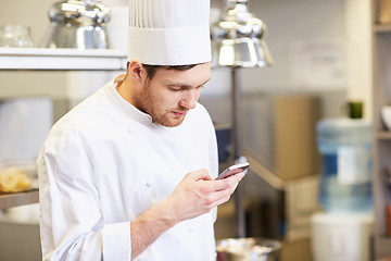 Image showing chef cook with smartphone at restaurant kitchen
