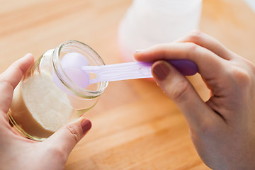 Image showing hands with jar and scoop making formula milk