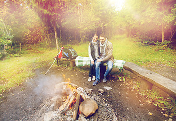 Image showing happy couple sitting on bench near camp fire