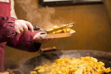 Image showing cook with fried potato on plate and turner