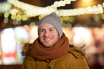 Image showing happy young man over christmas lights in winter