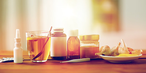 Image showing drugs, thermometer, honey and cup of tea on wood