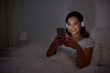 Image showing woman with smartphone and headphones in bed