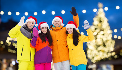 Image showing friends in santa hats and ski suits at christmas