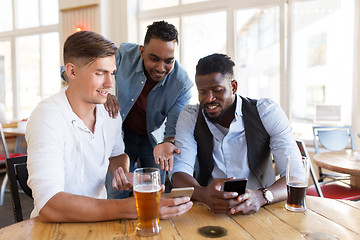 Image showing male friends with smartphone drinking beer at bar