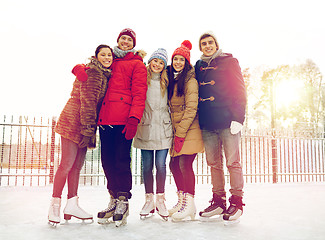 Image showing happy friends ice skating on rink outdoors