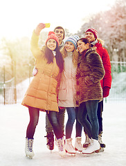 Image showing happy friends with smartphone on ice skating rink