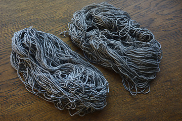 Image showing coils of gray wool on a wooden table