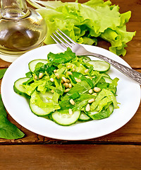 Image showing Salad from spinach and cucumbers with fork on wooden table