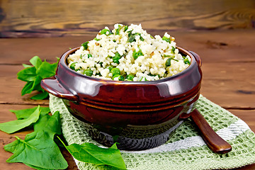 Image showing Couscous with spinach and green peas in bowl on wooden board