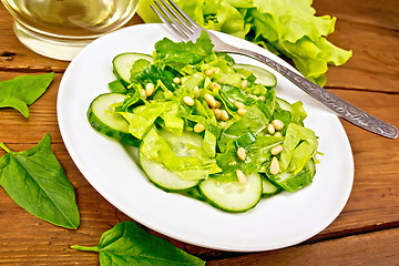 Image showing Salad from spinach and cucumber with fork on wooden board
