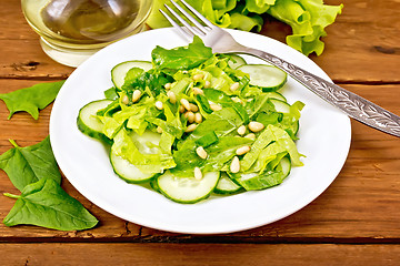 Image showing Salad from spinach and cucumbers with cedar nuts on table