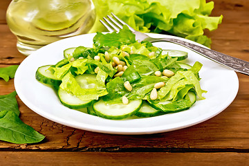 Image showing Salad from spinach and cucumber with fork on board