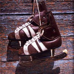 Image showing vintage pair of mens  ice skates hanging on a wooden wall