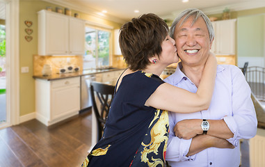 Image showing Happy Senior Chinese Couple Kissing Inside Beautiful Custom Kitc