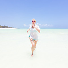 Image showing Young active woman having fun running and splashing in shellow sea water.