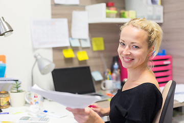 Image showing Business woman talking on mobile phone accepting papers.