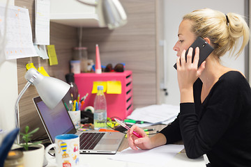 Image showing Female entrepreneur talking on mobile phone in colorful modern creative working environment.