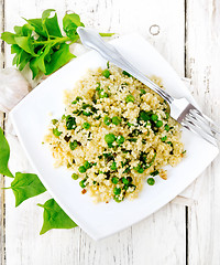 Image showing Couscous with spinach and green peas in plate on board top