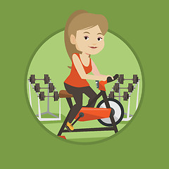 Image showing Young woman riding stationary bicycle.