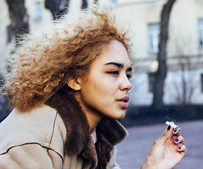 Image showing young pretty girl teenage outside smoking cigarette, looking lik