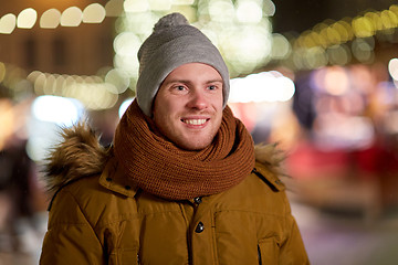 Image showing happy young man over christmas lights in winter