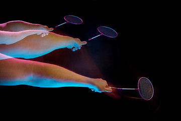 Image showing The hands of young man playing badminton over black background